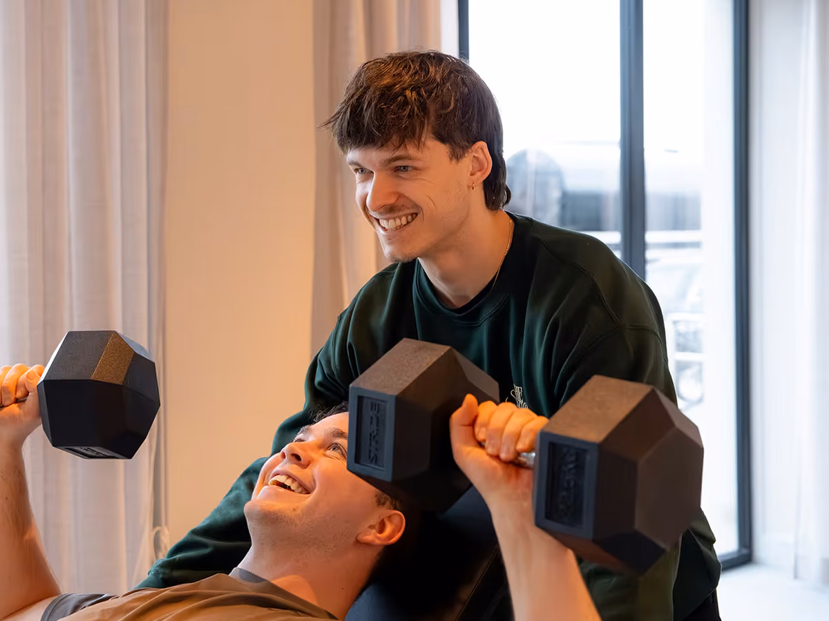 Een coach begeleidt een sessie met dumbbells