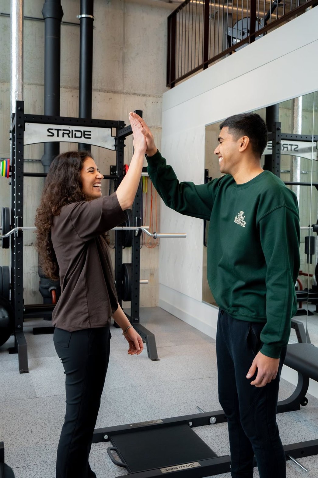 Coach en lid geven elkaar een high five in de club
