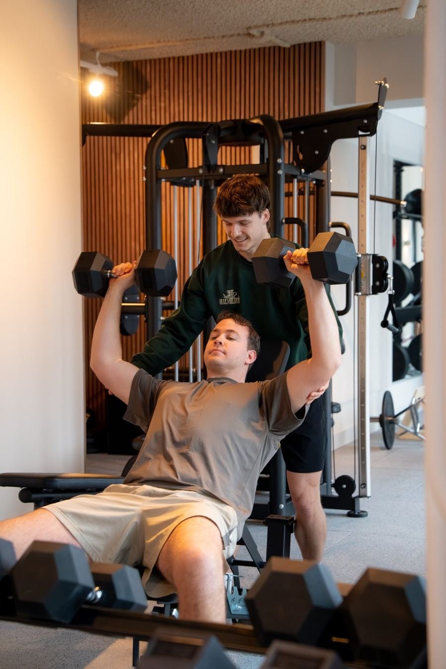Coach begeleidt een lid bij het trainen met losse gewichten